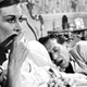 Woman eating grapes in bed next to sleeping husband